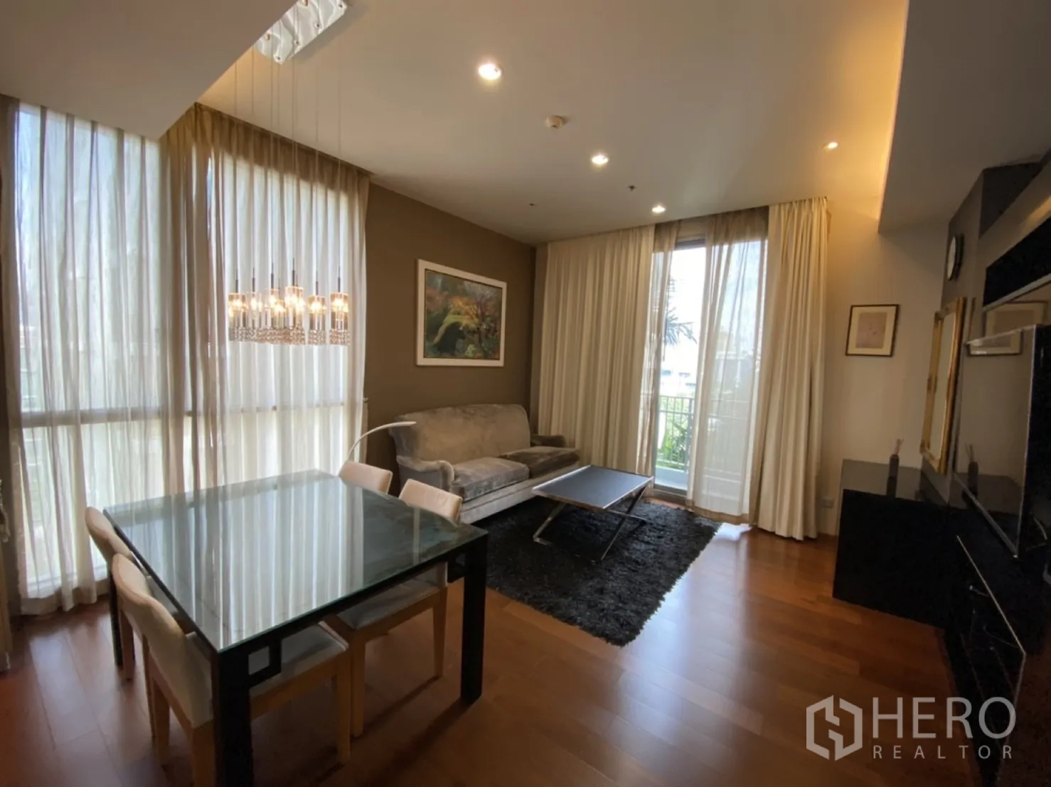 คอนโด ให้เช่าในWatthana, Bangkok - พื้นที่นั่งเล่นและทานอาหารสว่างโปร่ง มีผ้าม่านสูงจรดเพดาน โต๊ะทานอาหารกระจก โซฟา และประตูระเบียง