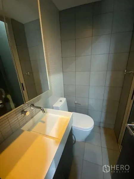 สำนักงาน ให้เช่าในPhaya Thai, Bangkok - ห้องน้ำสมัยใหม่พร้อมอ่างล้างหน้าแบบติดผนัง กระจกบานใหญ่ และผนังกระเบื้องสีเทา