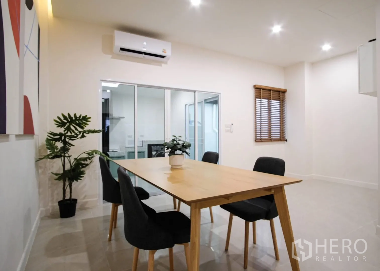 Townhouse for rent in Bang Phli, Samut Prakan - Dining area view toward glass doors to the kitchen and a window with blinds.