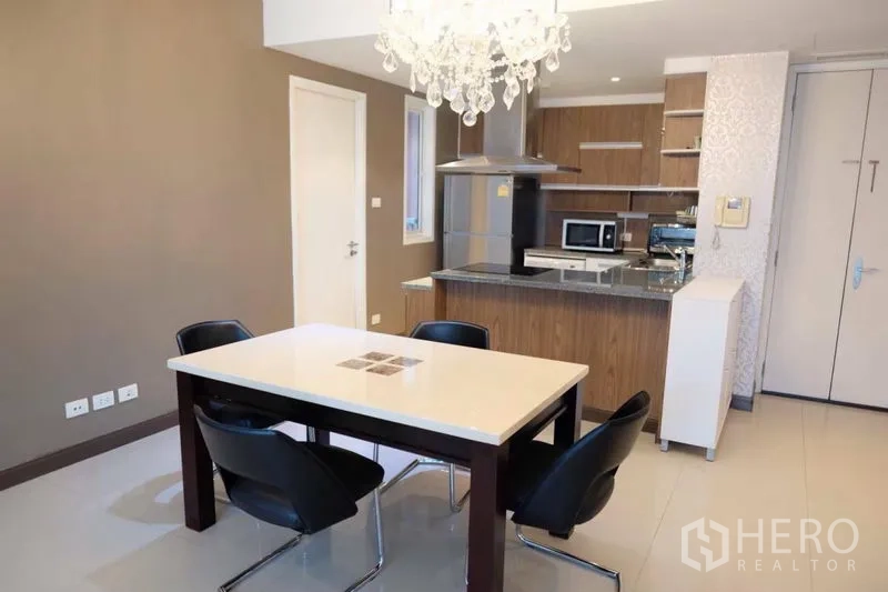 Condominium for rent in Watthana, Bangkok - Dining area with crystal chandelier adjoining an open-plan kitchen.