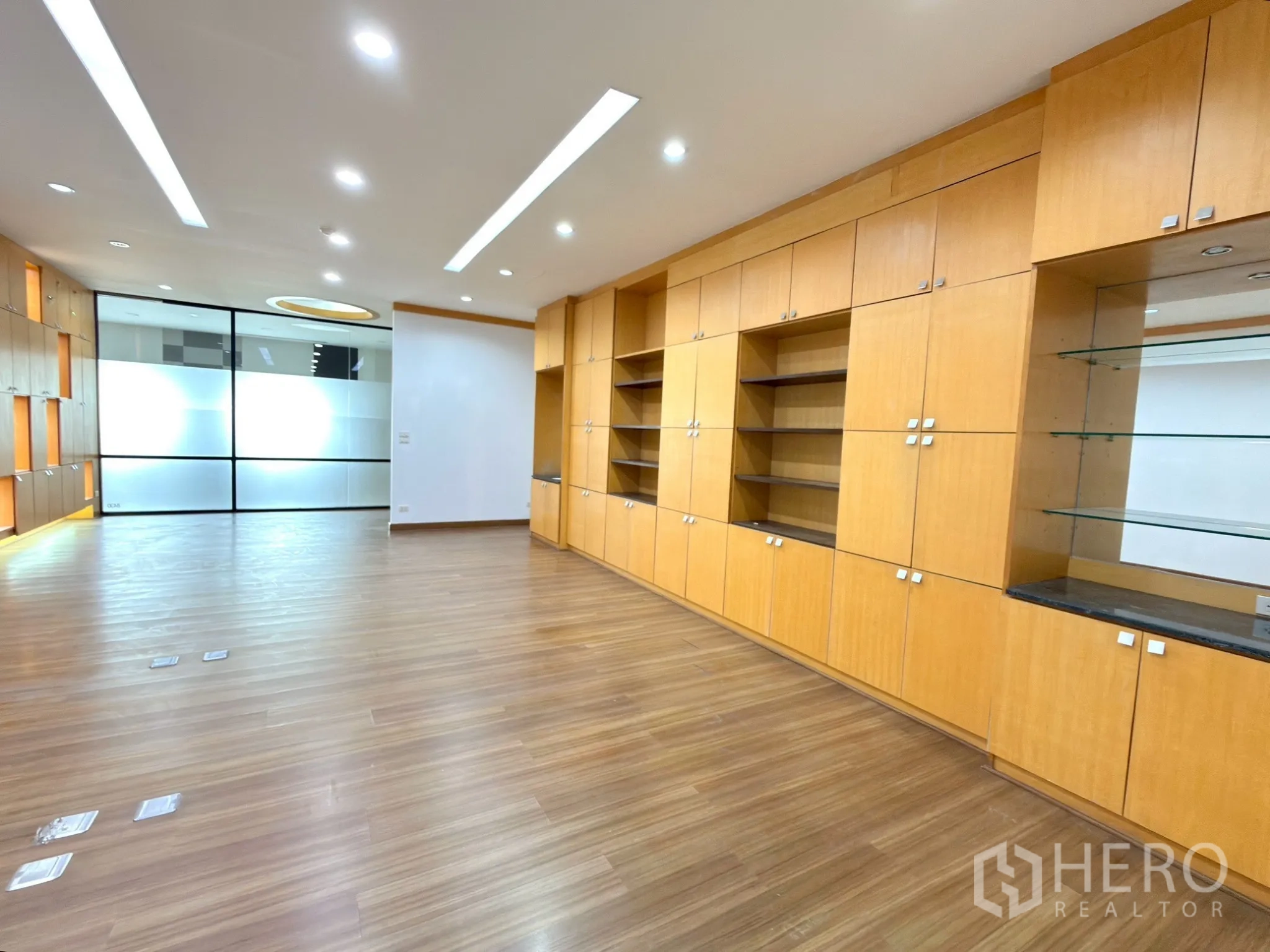 Office Space for rent in Watthana, Bangkok - Wall of wood cabinetry with glass shelves facing a frosted glass partition.