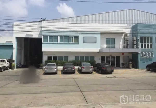 Factory for rent or sale in Bang Phli, Samut Prakan - Two-storey factory exterior in Bang Phli with front parking and a wide roller-shutter loading bay.