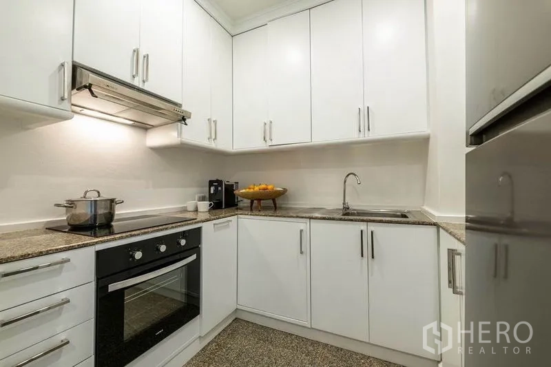 คอนโด ให้เช่าหรือขายในKhlong San, Bangkok - ครัวรูปตัวแอลตู้สีขาว พร้อมเตาอบบิวท์อินและเตาไฟฟ้า