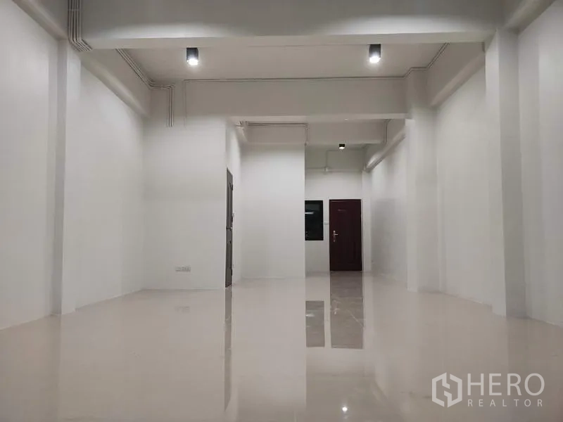 Home Office for sale in Lam Luk Ka, Pathum Thani - Ground-floor open-plan space with white walls and glossy tiled floor.