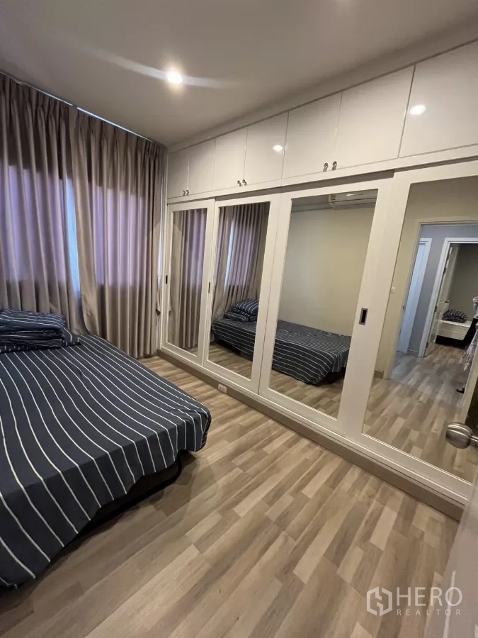 Detached House for rent in Suan Luang, Bangkok - Bedroom with built-in mirrored wardrobes and wood laminate flooring