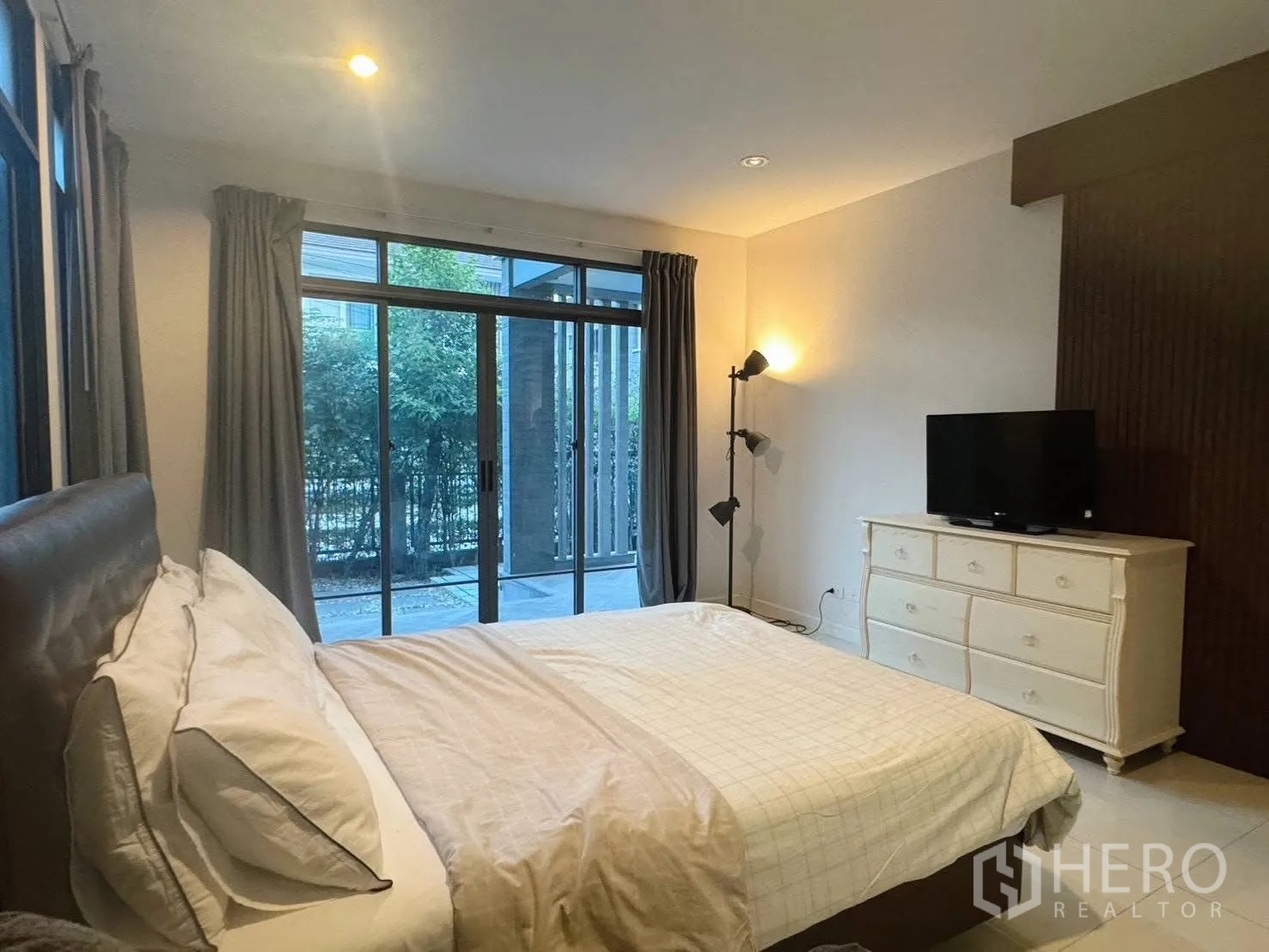 Detached House for rent or sale in Suan Luang, Bangkok - Bedroom with sliding glass doors to patio, dresser and TV.