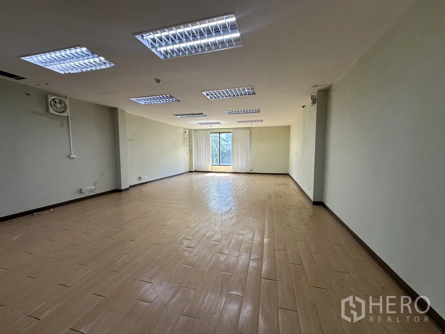 Home Office for rent in Prawet, Bangkok - Large empty office room with fluorescent ceiling lights and a window at the end.