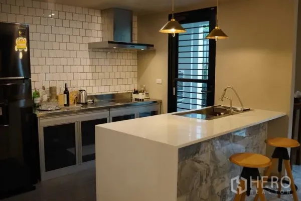 公寓 出租在Watthana, Bangkok - 现代厨房，石材中岛吧台、吊灯与地铁砖墙面。