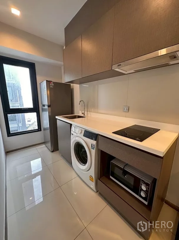 Condominium for rent in Chatuchak, Bangkok - Enclosed galley kitchen with fridge, washer, cooktop and microwave.