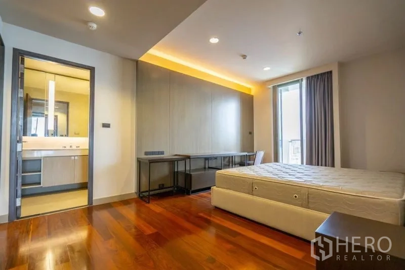 คอนโด ให้เช่าในKhlong Toei, Bangkok - ห้องนอนมีห้องน้ำในตัว พร้อมโต๊ะบิวท์อิน แสงไฟโทนอุ่น และทางเข้าไปยังห้องน้ำ