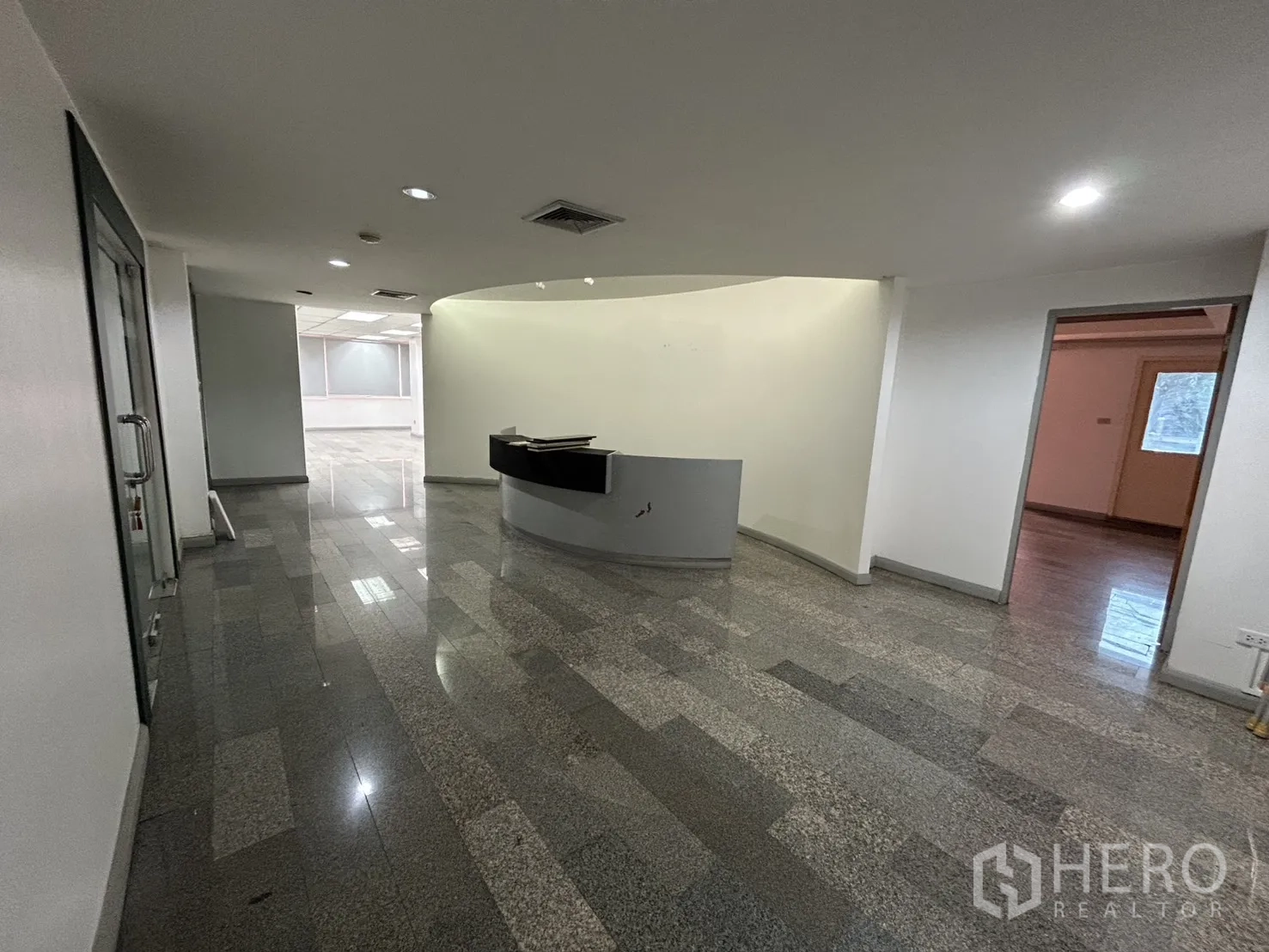 ออฟฟิศ for rent in Khlong Toei, Bangkok - โถงต้อนรับพร้อมเคาน์เตอร์โค้ง ไฟดาวน์ไลท์ และทางเชื่อมสู่ออฟฟิศด้านใน