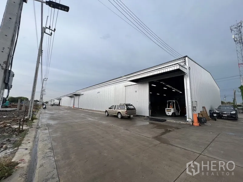 คลังสินค้า ให้เช่าในLat Krabang, Bangkok - ด้านหน้าโกดังเหล็กผนังลอน ประตูม้วนสูง รถฟอร์คลิฟต์และที่จอดรถริมถนนบริการกว้าง
