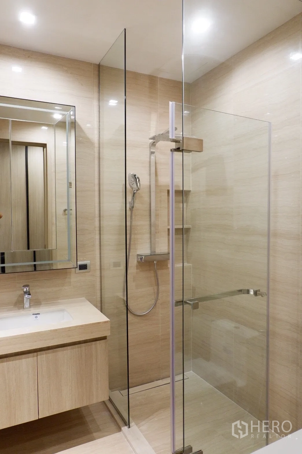 公寓 出租在Watthana, Bangkok - 现代浴室，玻璃淋浴间、手持花洒，浅木色洗手台与镜柜。