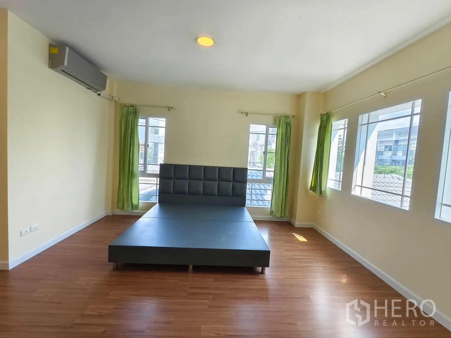 Detached House for rent in Bang Kapi, Bangkok - Sunlit master bedroom with multiple windows and wood floors.