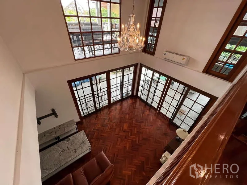 Detached House for rent in Chatuchak, Bangkok - Double-height living area viewed from above with chandelier and tall windows.
