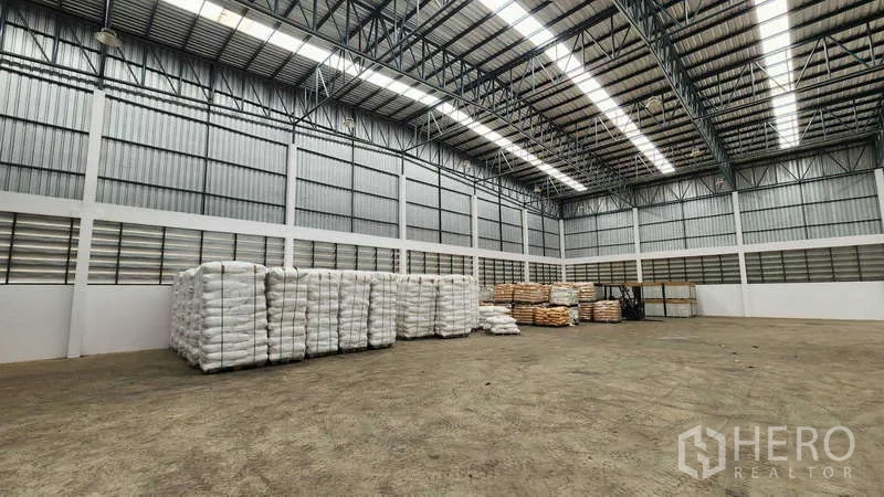 货栈 出租在Ban Phaeo, Samut Sakhon - 宽阔储存区，金属夹芯板墙面，袋装货物整齐排列。