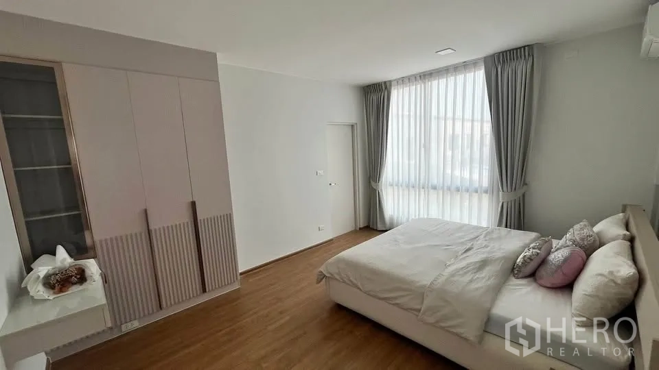 Townhouse for rent or sale in Bang Phli, Samut Prakan - Spacious bedroom with double bed and floor‑to‑ceiling curtained window.