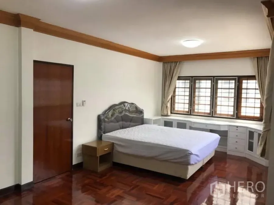 Detached House for rent in Khlong Toei, Bangkok - Master bedroom with bed, bay-style windows and built-in cabinetry