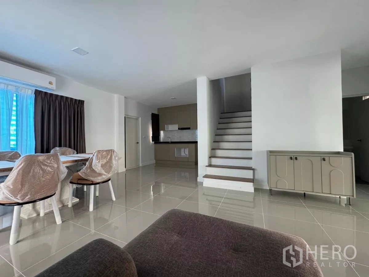 Detached House for rent in Bang Phli, Samut Prakan - Living space facing the staircase and a fitted kitchen with cabinets and sink.