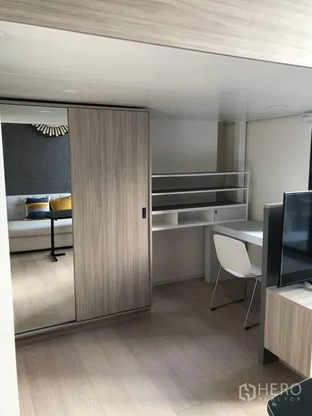 Condominium for sale in Ratchathewi, Bangkok - Workstation with shelves beside a sliding mirrored wardrobe in a modern condo living space.