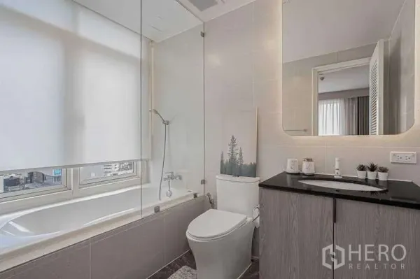 คอนโด ให้เช่าหรือขายในWatthana, Bangkok - ห้องน้ำพร้อมอ่างอาบน้ำริมหน้าต่าง เคาน์เตอร์ลอย และแสงไฟนุ่มนวล.