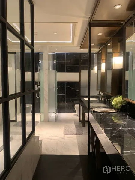 Condominium for rent in Khlong Toei, Bangkok - Luxurious master bathroom with double vanity, black stone counters and partitioned shower.