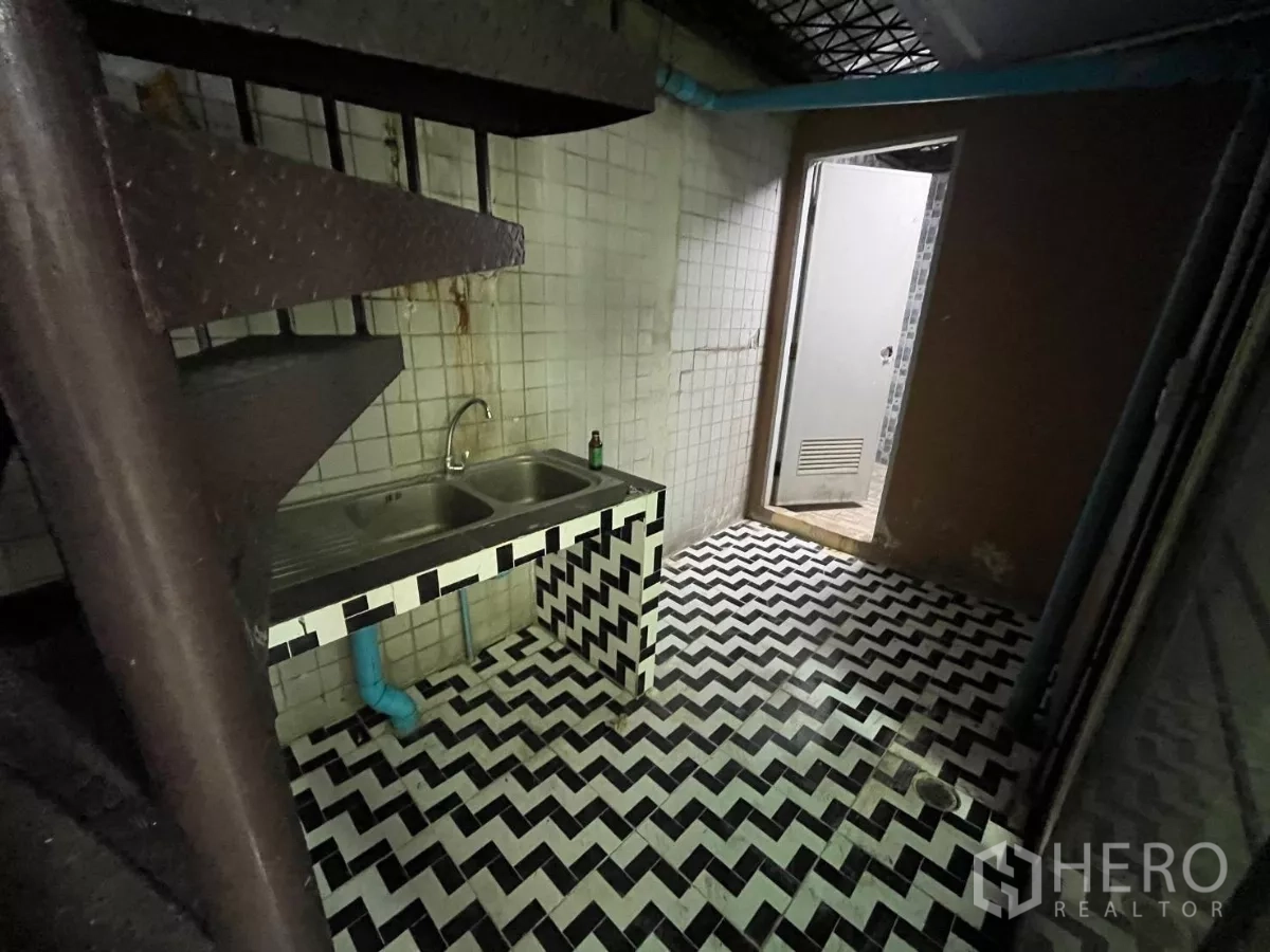 อาคารพาณิชย์ ให้เช่าในWatthana, Bangkok - โซนใช้งานพร้อมอ่างล้างจานสแตนเลสคู่ พื้นกระเบื้องก้างปลา และบันไดเวียนข้างประตูห้องน้ำ