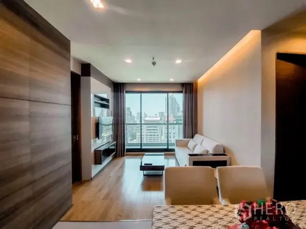 公寓 出租在Bang Rak, Bangkok - 宽敞客厅面向落地窗与阳台，远眺城市全景。