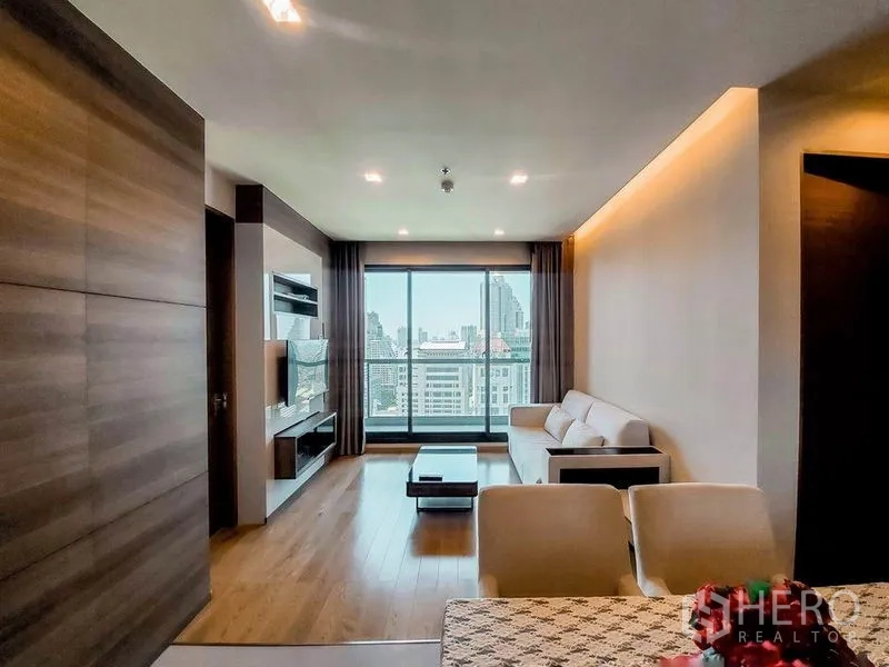 公寓 出租在Bang Rak, Bangkok - 宽敞客厅面向落地窗与阳台，远眺城市全景。