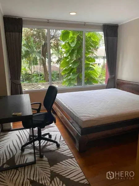 Condominium for rent in Pathum Wan, Bangkok - Bright bedroom with desk, large window and garden view in Bangkok condo.