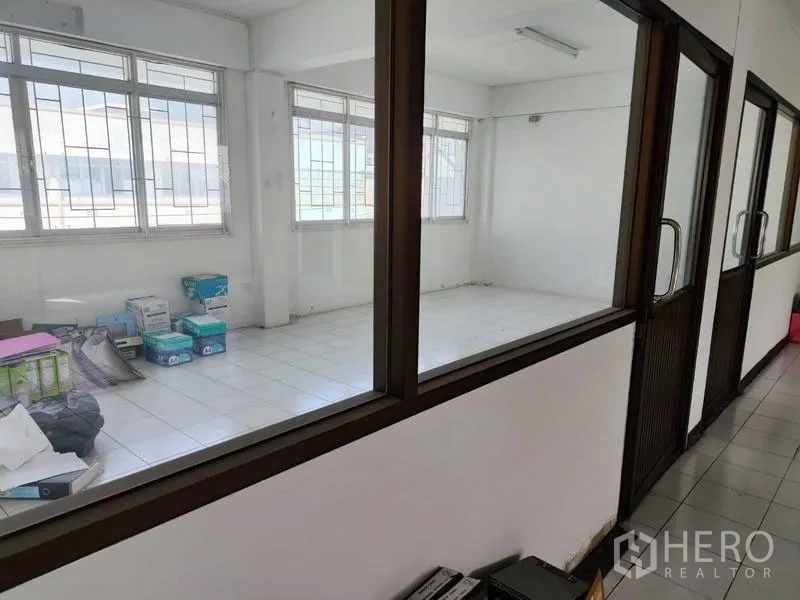 Shophouse for sale in Pathum Thani - Corridor lined with glass offices and windows bringing natural light.