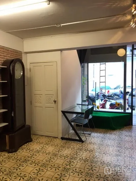 零售空间 出租在Khlong Toei, Bangkok - 临街前场带整面玻璃橱窗、白色门与窗边座位，可见街景。