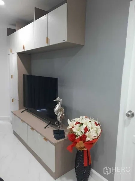 公寓 出租或出售在Khlong Toei, Bangkok - 客厅电视墙，内置储物柜与装饰摆件。