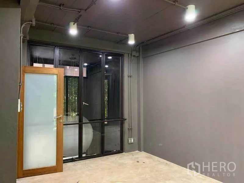 สำนักงานที่บ้าน ให้เช่าในHuai Khwang, Bangkok - ห้องโล่งโทนเทามีประตูกระจกฝ้าและหน้าต่างกรอบดำ.