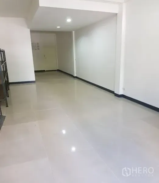 店屋 出租在Watthana, Bangkok - 一层开放式空间，亮面地砖、白墙与嵌入式照明。