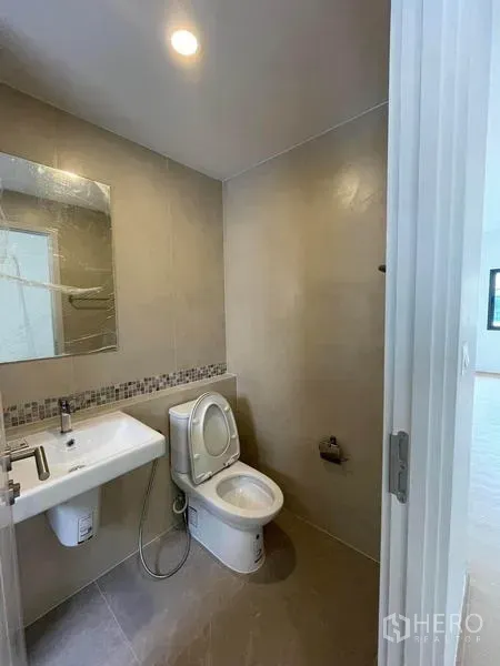 ทาวน์เฮาส์ ให้เช่าในPrawet, Bangkok - ห้องน้ำขนาดกะทัดรัด มีโถสุขภัณฑ์ อ่างล้างหน้า กระจก และผนังกระเบื้องโทนอบอุ่น