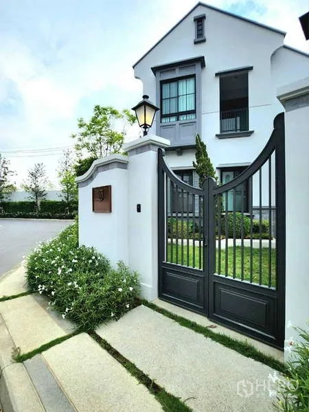 Detached House for rent in Saphan Sung, Bangkok - Pedestrian gate with lantern leading to manicured garden and white facade of the house.