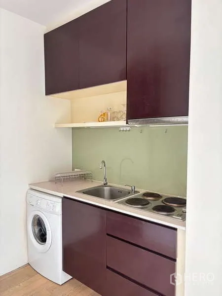 คอนโด ให้เช่าในBangkok - ครัวบิวท์อินขนาดเล็ก เตาไฟฟ้า อ่างล้างจาน ตู้เก็บของ และเครื่องซักผ้าแบบฝาหน้า