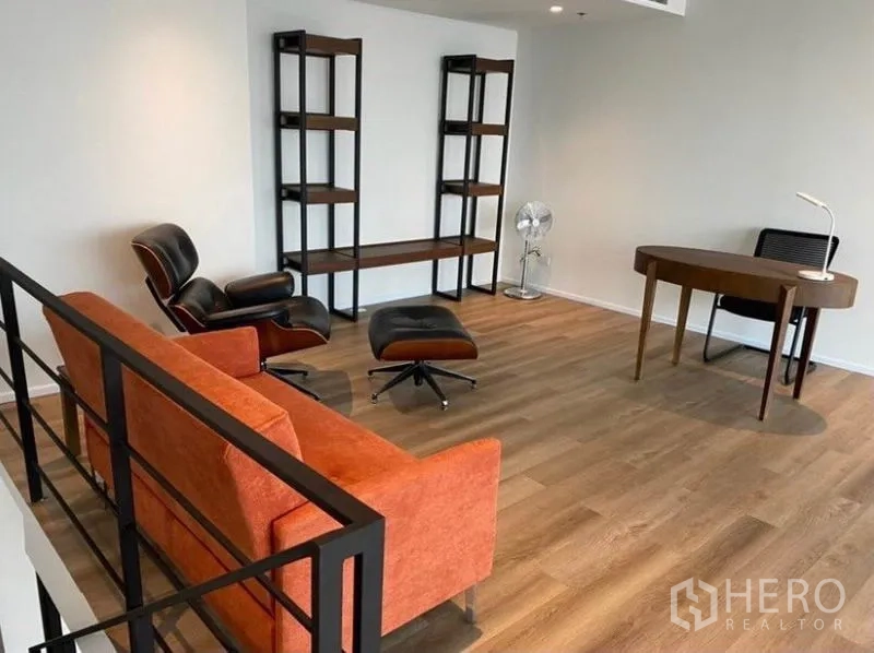 公寓 出租在Bang Rak, Bangkok - 夹层书房/休闲区，配书桌、置物架、橙色沙发与休闲椅。