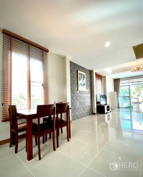 ทาวน์เฮาส์ ให้เช่าในPrawet, Bangkok - มุมรับประทานอาหารโต๊ะไม้ ข้างหน้าต่างสูง มองสู่พื้นที่นั่งเล่นและประตูสไลด์หน้าบ้าน.