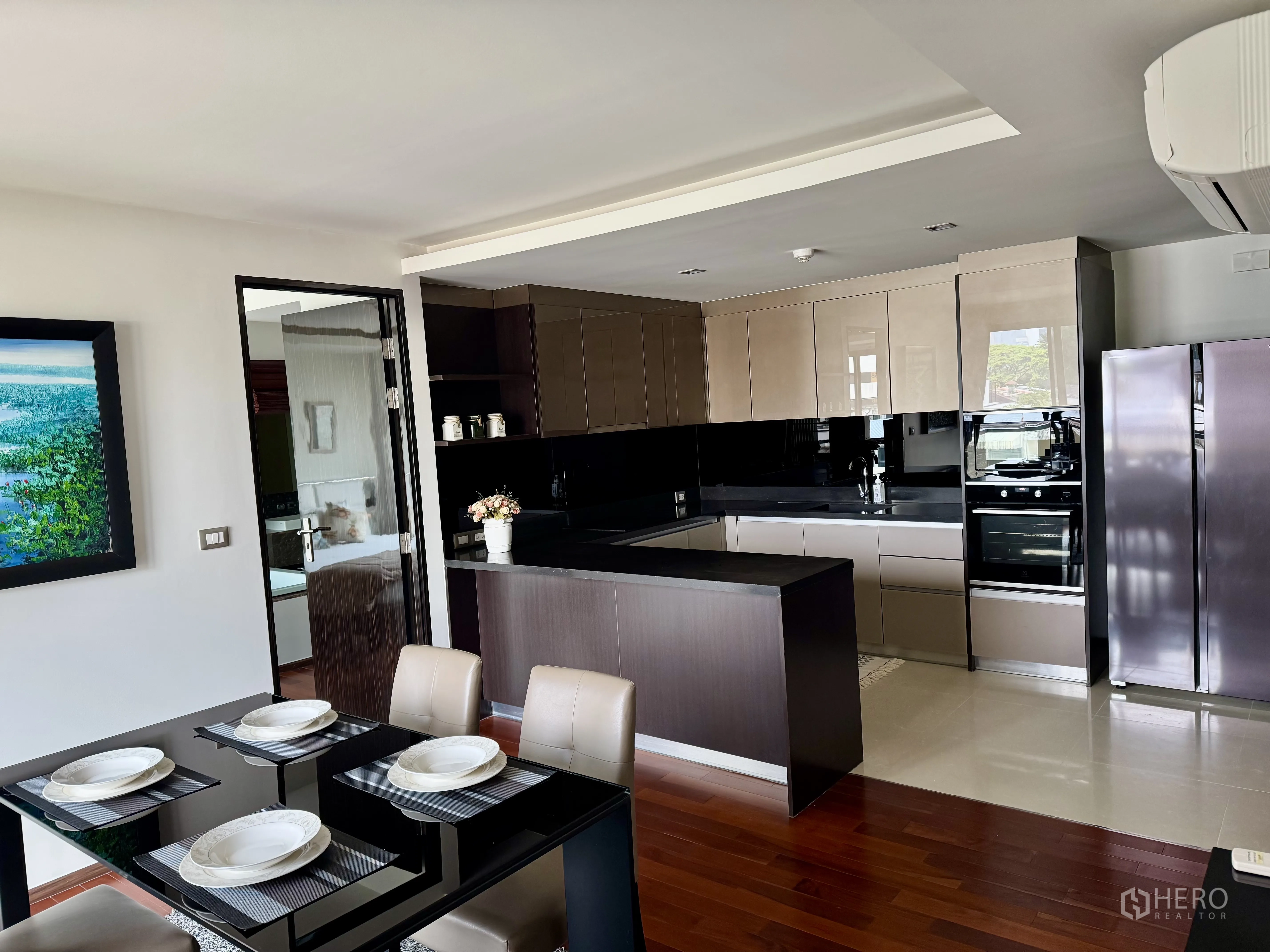 Condominium for rent in Watthana, Bangkok - Open-plan kitchen with glossy cabinets, island, stainless refrigerator, and dining table.