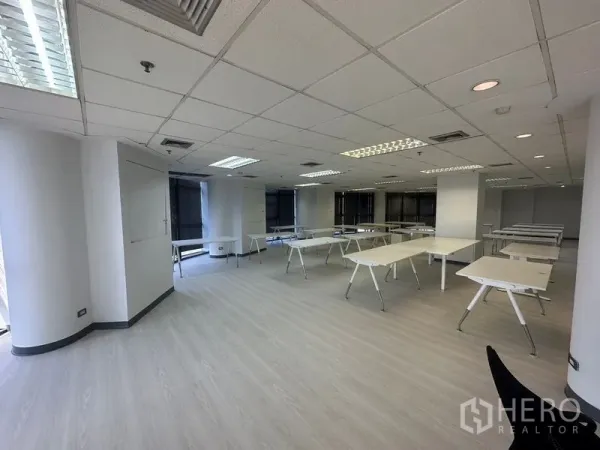 办公空间 出租 - 宽敞办公区，多张桌子，弧形转角窗与充足照明。