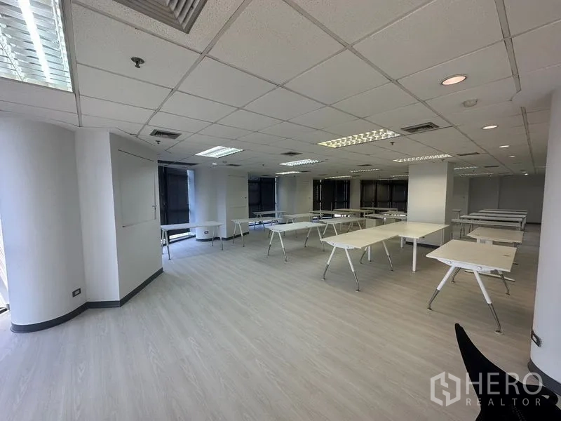 办公空间 出租 - 宽敞办公区，多张桌子，弧形转角窗与充足照明。