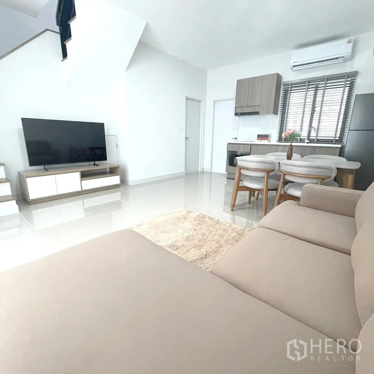 Townhouse for rent in Bang Phli, Samut Prakan - Open-plan living and dining area with sofa, TV, and kitchen in the background.