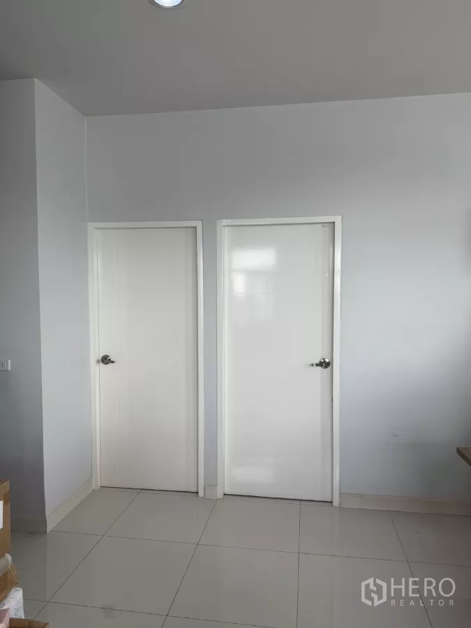 Factory for sale in Lam Luk Ka, Pathum Thani - Interior corridor with two white doors and glossy tiled floor.