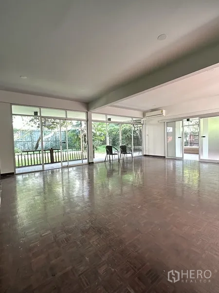 Detached House for rent in Khlong Toei, Bangkok - Bright living area with large windows overlooking the garden and minimal furniture.