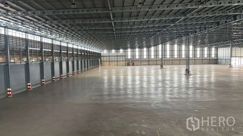 Warehouse for rent in Bang Phli, Samut Prakan - Wide warehouse bay with dock‑high roller doors, column grid, and open staging area for trucks and forklifts.