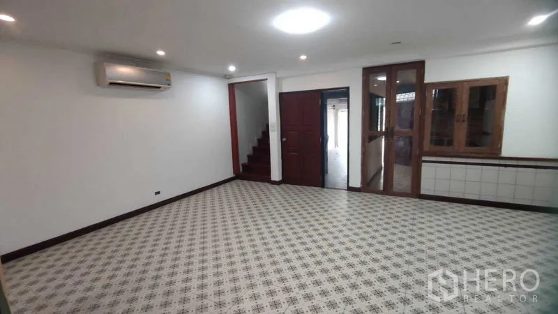 Home Office for rent in Watthana, Bangkok - Living room view showing staircase, front door and wall-mounted air conditioner.