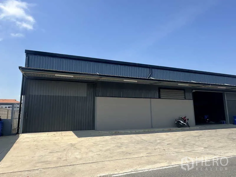 Warehouse for rent in Bang Bua Thong, Nonthaburi - Front facade of the warehouse with multiple roller doors and a concrete forecourt.