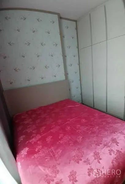 Condominium for rent or sale - Cozy second bedroom with floral wallpaper, tall wardrobe and pink bedspread.